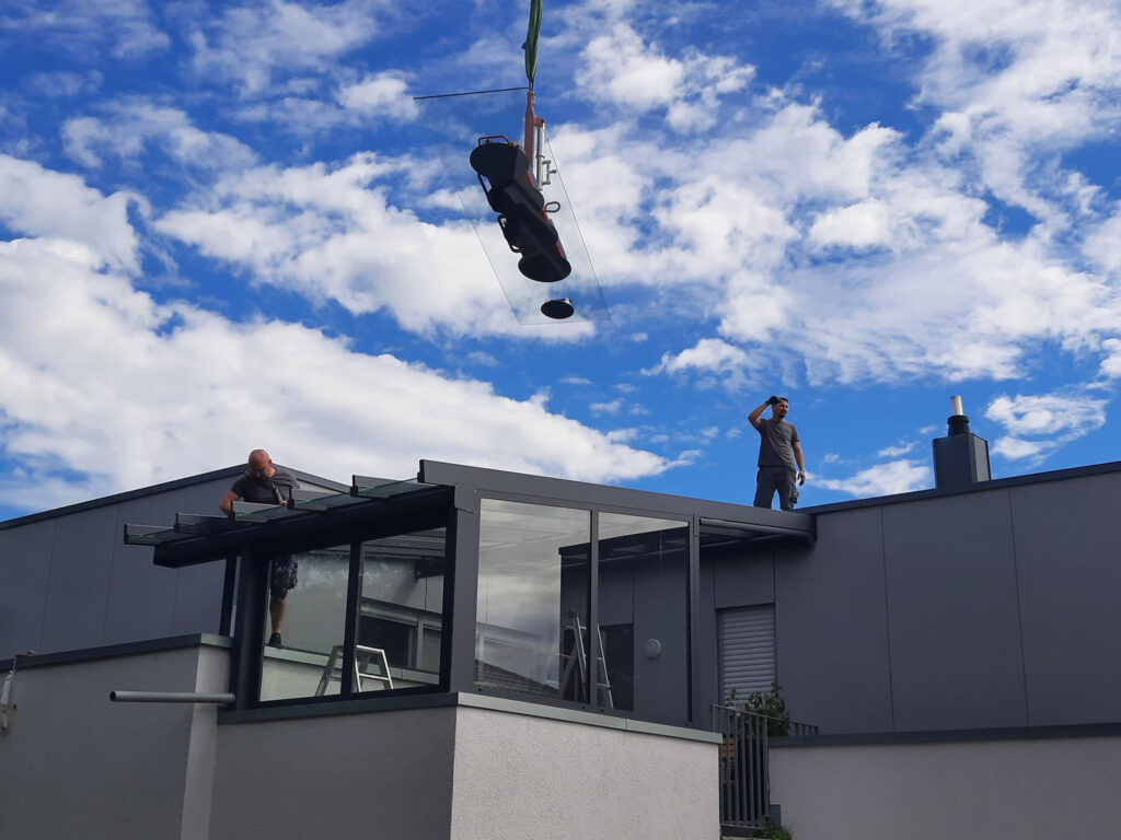 Montage einer großformatigen Glasscheibe für eine Estate Eingangsüberdachung mithilfe eines Krans