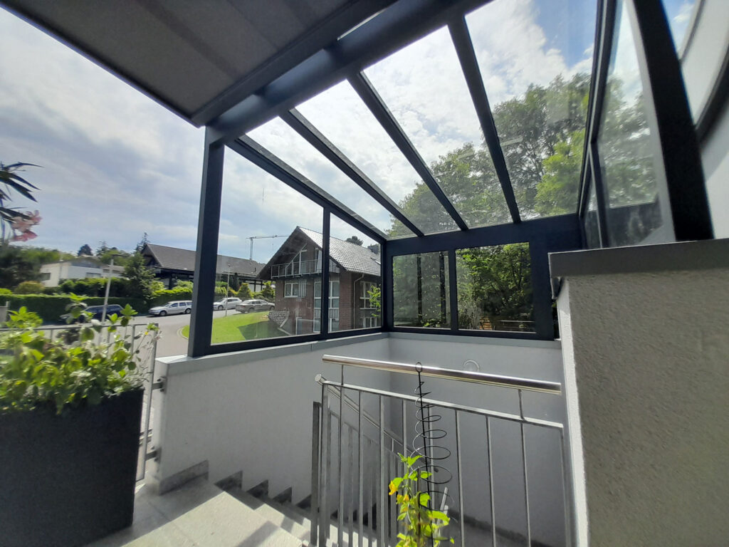 Großzügige Estate Eingangsüberdachung mit Glasdach und seitlicher Verglasung an einem Wohnhaus